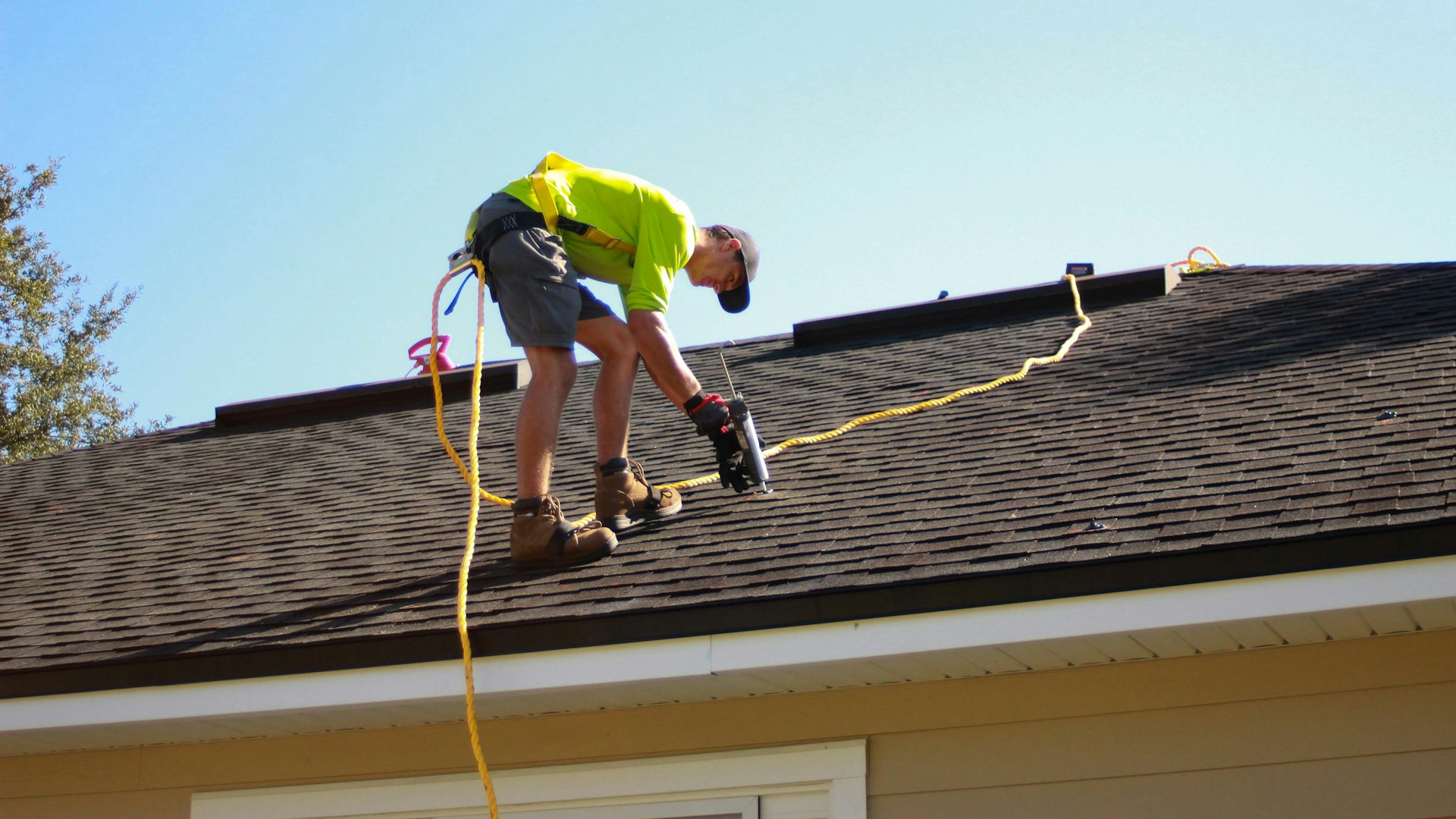 A roofer driving a screw into decking with a cordless drill
