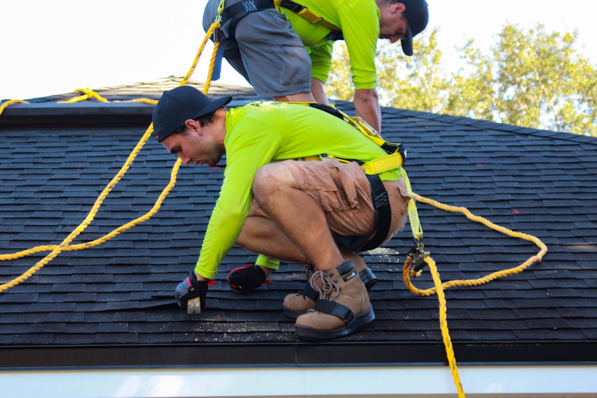 Two roofers working on the deck of a residential roof