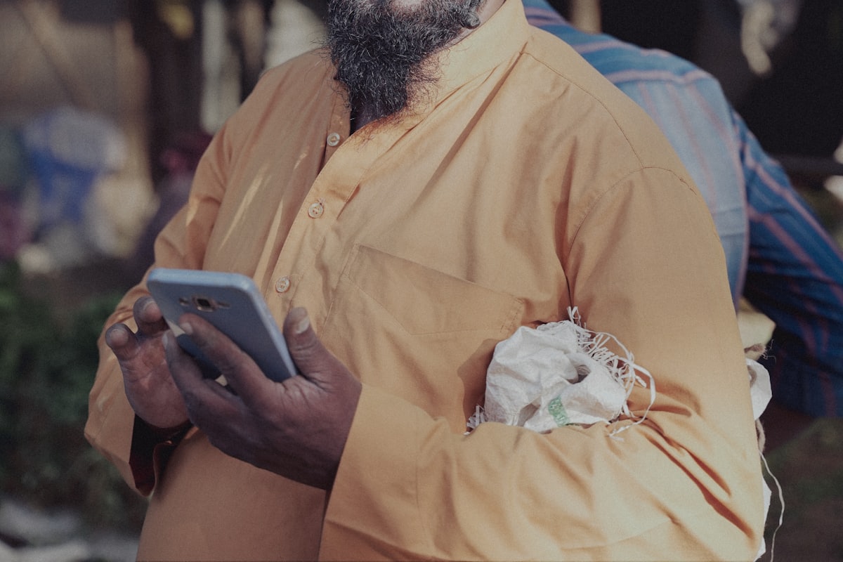 A worker in a hard hat reviewing job information on a handheld screen